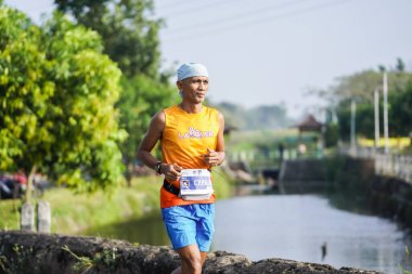 Jogja Maratonu 42K 'nın katılımcıları veya koşucuları, Prambanan tapınak köyünün etrafından güzel bir yoldan geçiyorlar. : Yogyakarta, Endonezya - 18 Haziran 2023