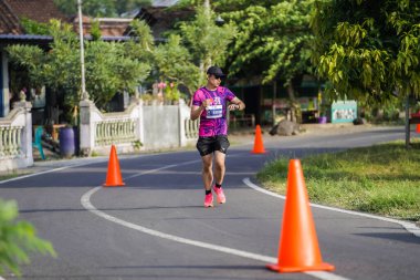 Jogja Maratonu 42K 'nın katılımcıları veya koşucuları, Prambanan tapınak köyünün etrafından güzel bir yoldan geçiyorlar. : Yogyakarta, Endonezya - 18 Haziran 2023
