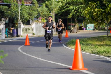 Jogja Maratonu 42K 'nın katılımcıları veya koşucuları, Prambanan tapınak köyünün etrafından güzel bir yoldan geçiyorlar. : Yogyakarta, Endonezya - 18 Haziran 2023