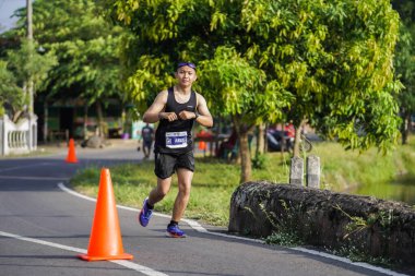 Jogja Maratonu 42K 'nın katılımcıları veya koşucuları, Prambanan tapınak köyünün etrafından güzel bir yoldan geçiyorlar. : Yogyakarta, Endonezya - 18 Haziran 2023