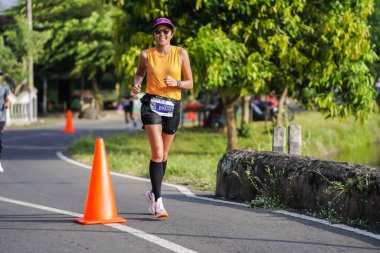 Jogja Maratonu 42K 'nın katılımcıları veya koşucuları, Prambanan tapınak köyünün etrafından güzel bir yoldan geçiyorlar. : Yogyakarta, Endonezya - 18 Haziran 2023