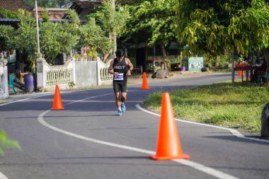 Jogja Maratonu 42K 'nın katılımcıları veya koşucuları, Prambanan tapınak köyünün etrafından güzel bir yoldan geçiyorlar. : Yogyakarta, Endonezya - 18 Haziran 2023