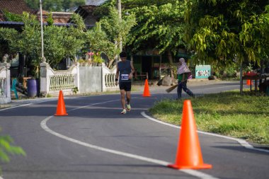 Jogja Maratonu 42K 'nın katılımcıları veya koşucuları, Prambanan tapınak köyünün etrafından güzel bir yoldan geçiyorlar. : Yogyakarta, Endonezya - 18 Haziran 2023