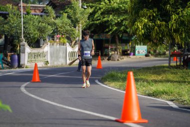 Jogja Maratonu 42K 'nın katılımcıları veya koşucuları, Prambanan tapınak köyünün etrafından güzel bir yoldan geçiyorlar. : Yogyakarta, Endonezya - 18 Haziran 2023