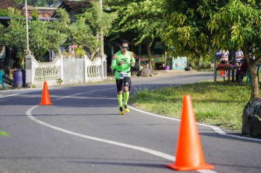 Jogja Maratonu 42K 'nın katılımcıları veya koşucuları, Prambanan tapınak köyünün etrafından güzel bir yoldan geçiyorlar. : Yogyakarta, Endonezya - 18 Haziran 2023