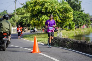 Jogja Maratonu 42K 'nın katılımcıları veya koşucuları, Prambanan tapınak köyünün etrafından güzel bir yoldan geçiyorlar. : Yogyakarta, Endonezya - 18 Haziran 2023