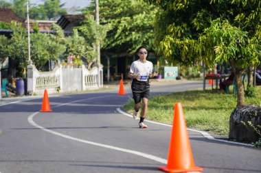 Jogja Maratonu 42K 'nın katılımcıları veya koşucuları, Prambanan tapınak köyünün etrafından güzel bir yoldan geçiyorlar. : Yogyakarta, Endonezya - 18 Haziran 2023