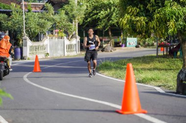 Jogja Maratonu 42K 'nın katılımcıları veya koşucuları, Prambanan tapınak köyünün etrafından güzel bir yoldan geçiyorlar. : Yogyakarta, Endonezya - 18 Haziran 2023