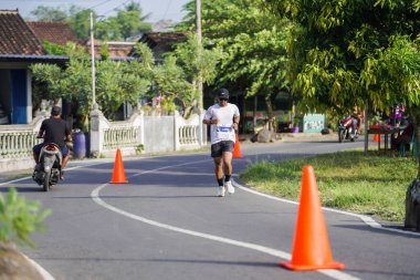 Jogja Maratonu 42K 'nın katılımcıları veya koşucuları, Prambanan tapınak köyünün etrafından güzel bir yoldan geçiyorlar. : Yogyakarta, Endonezya - 18 Haziran 2023