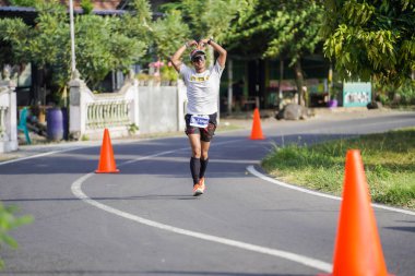 Jogja Maratonu 42K 'nın katılımcıları veya koşucuları, Prambanan tapınak köyünün etrafından güzel bir yoldan geçiyorlar. : Yogyakarta, Endonezya - 18 Haziran 2023