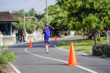 Jogja Maratonu 42K 'nın katılımcıları veya koşucuları, Prambanan tapınak köyünün etrafından güzel bir yoldan geçiyorlar. : Yogyakarta, Endonezya - 18 Haziran 2023