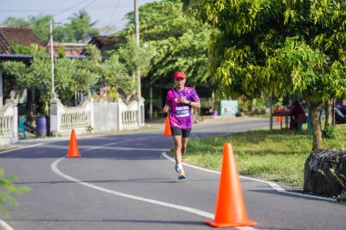 Jogja Maratonu 42K 'nın katılımcıları veya koşucuları, Prambanan tapınak köyünün etrafından güzel bir yoldan geçiyorlar. : Yogyakarta, Endonezya - 18 Haziran 2023