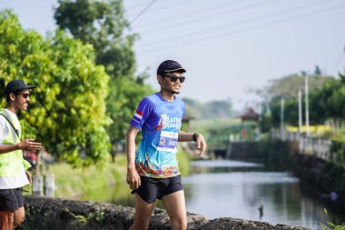 Jogja Maratonu 42K 'nın katılımcıları veya koşucuları, Prambanan tapınak köyünün etrafından güzel bir yoldan geçiyorlar. : Yogyakarta, Endonezya - 18 Haziran 2023