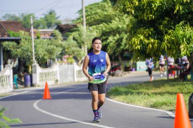 Jogja Maratonu 42K 'nın katılımcıları veya koşucuları, Prambanan tapınak köyünün etrafından güzel bir yoldan geçiyorlar. : Yogyakarta, Endonezya - 18 Haziran 2023