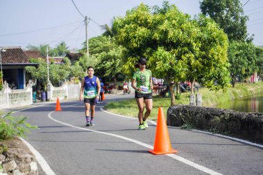 Jogja Maratonu 42K 'nın katılımcıları veya koşucuları, Prambanan tapınak köyünün etrafından güzel bir yoldan geçiyorlar. : Yogyakarta, Endonezya - 18 Haziran 2023