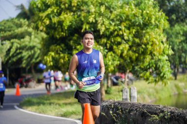 Jogja Maratonu 42K 'nın katılımcıları veya koşucuları, Prambanan tapınak köyünün etrafından güzel bir yoldan geçiyorlar. : Yogyakarta, Endonezya - 18 Haziran 2023