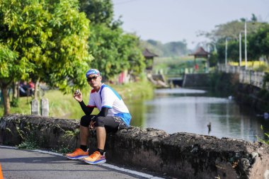 Jogja Maratonu 42K 'nın katılımcıları veya koşucuları, Prambanan tapınak köyünün etrafından güzel bir yoldan geçiyorlar. : Yogyakarta, Endonezya - 18 Haziran 2023