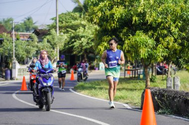 Jogja Maratonu 42K 'nın katılımcıları veya koşucuları, Prambanan tapınak köyünün etrafından güzel bir yoldan geçiyorlar. : Yogyakarta, Endonezya - 18 Haziran 2023