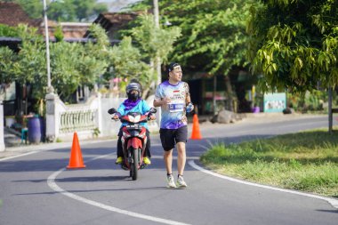 Jogja Maratonu 42K 'nın katılımcıları veya koşucuları, Prambanan tapınak köyünün etrafından güzel bir yoldan geçiyorlar. : Yogyakarta, Endonezya - 18 Haziran 2023
