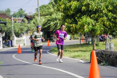 Jogja Maratonu 42K 'nın katılımcıları veya koşucuları, Prambanan tapınak köyünün etrafından güzel bir yoldan geçiyorlar. : Yogyakarta, Endonezya - 18 Haziran 2023