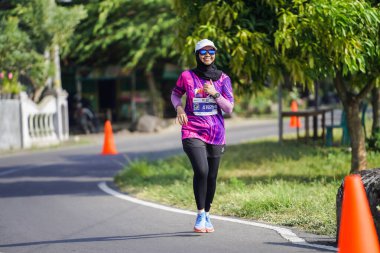 Jogja Maratonu 42K 'nın katılımcıları veya koşucuları, Prambanan tapınak köyünün etrafından güzel bir yoldan geçiyorlar. : Yogyakarta, Endonezya - 18 Haziran 2023