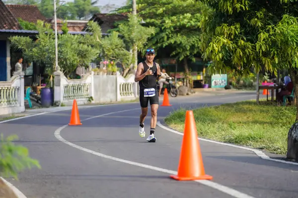 Jogja Maratonu 42K 'nın katılımcıları veya koşucuları, Prambanan tapınak köyünün etrafından güzel bir yoldan geçiyorlar. : Yogyakarta, Endonezya - 18 Haziran 2023