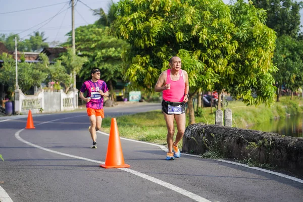 Jogja Maratonu 42K 'nın katılımcıları veya koşucuları, Prambanan tapınak köyünün etrafından güzel bir yoldan geçiyorlar. : Yogyakarta, Endonezya - 18 Haziran 2023