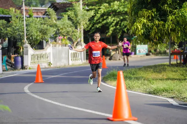 Jogja Maratonu 42K 'nın katılımcıları veya koşucuları, Prambanan tapınak köyünün etrafından güzel bir yoldan geçiyorlar. : Yogyakarta, Endonezya - 18 Haziran 2023