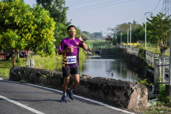 Jogja Maratonu 42K 'nın katılımcıları veya koşucuları, Prambanan tapınak köyünün etrafından güzel bir yoldan geçiyorlar. : Yogyakarta, Endonezya - 18 Haziran 2023