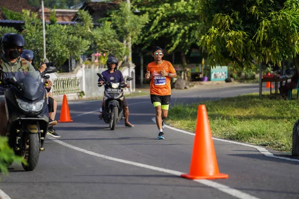 Jogja Maratonu 42K 'nın katılımcıları veya koşucuları, Prambanan tapınak köyünün etrafından güzel bir yoldan geçiyorlar. : Yogyakarta, Endonezya - 18 Haziran 2023