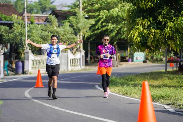 Jogja Maratonu 42K 'nın katılımcıları veya koşucuları, Prambanan tapınak köyünün etrafından güzel bir yoldan geçiyorlar. : Yogyakarta, Endonezya - 18 Haziran 2023