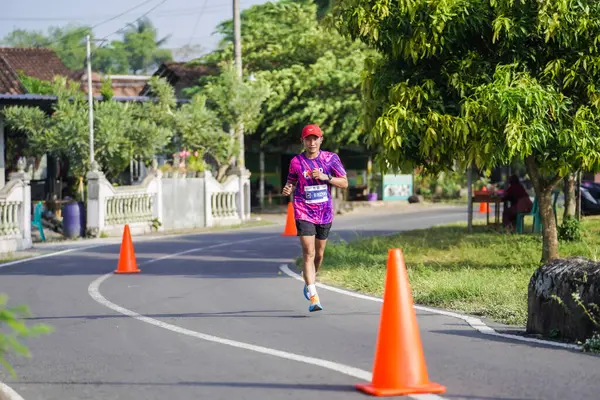 Jogja Maratonu 42K 'nın katılımcıları veya koşucuları, Prambanan tapınak köyünün etrafından güzel bir yoldan geçiyorlar. : Yogyakarta, Endonezya - 18 Haziran 2023