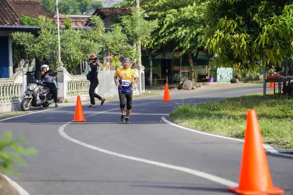 Jogja Maratonu 42K 'nın katılımcıları veya koşucuları, Prambanan tapınak köyünün etrafından güzel bir yoldan geçiyorlar. : Yogyakarta, Endonezya - 18 Haziran 2023