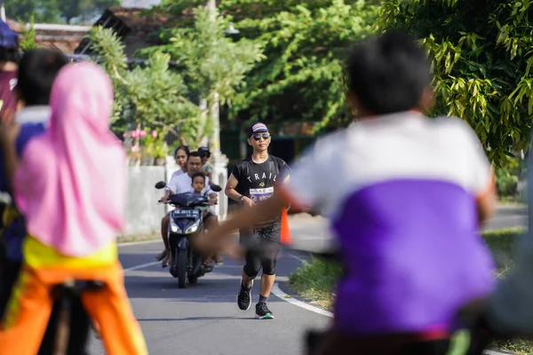 Jogja Maratonu 42K 'nın katılımcıları veya koşucuları, Prambanan tapınak köyünün etrafından güzel bir yoldan geçiyorlar. : Yogyakarta, Endonezya - 18 Haziran 2023