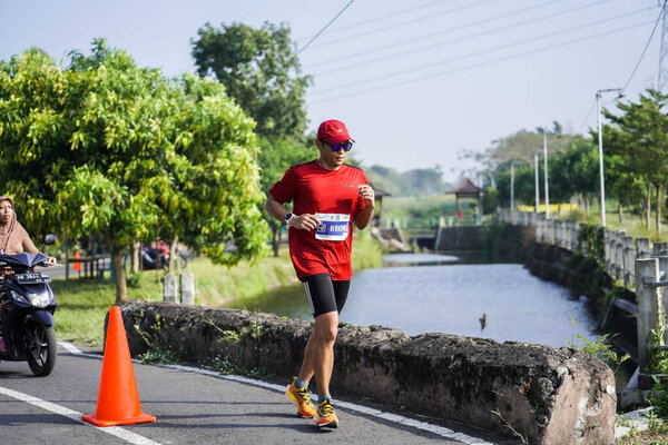 Участники или бегуны Джогджинского марафона 42К проходят красивый маршрут вокруг храма Прамбанан. : Джокьякарта, Индонезия - 18 июня 2023 года