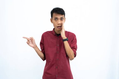 Asyalı bir adam, iş adamı ya da öğrenci konsepti, kırmızı günlük bir gömlek giyiyor, yan tarafları gösteriyor, el ele fısıldıyor, bilgi veriyor, beyaz arka planda izole edilmiş..