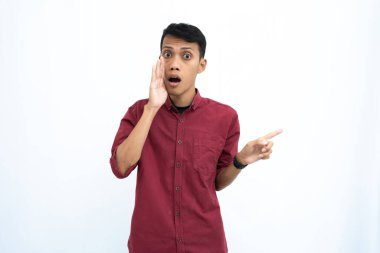 Asyalı bir adam, iş adamı ya da öğrenci konsepti, kırmızı günlük bir gömlek giyiyor, yan tarafları gösteriyor, el ele fısıldıyor, bilgi veriyor, beyaz arka planda izole edilmiş..