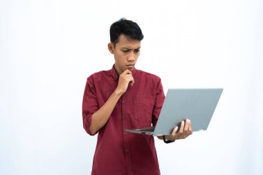 Asyalı bir adam, iş adamı ya da öğrenci konsepti kırmızı günlük kıyafetler giyip minimalist bir dizüstü bilgisayar taşıyor. İzole edilmiş beyaz arkaplan.
