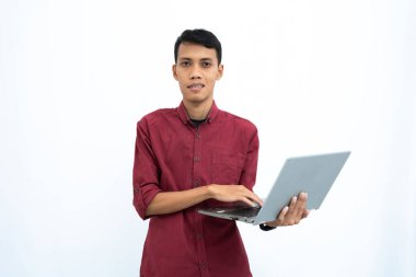 Asyalı bir adam, iş adamı ya da öğrenci konsepti kırmızı günlük kıyafetler giyip minimalist bir dizüstü bilgisayar taşıyor. İzole edilmiş beyaz arkaplan.