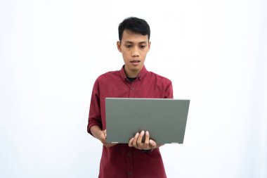 Asyalı bir adam, iş adamı ya da öğrenci konsepti kırmızı günlük kıyafetler giyip minimalist bir dizüstü bilgisayar taşıyor. İzole edilmiş beyaz arkaplan.