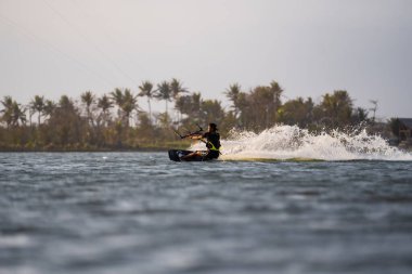 Uçurtma. Bir erkek sörfçü güzel bir köprü ve kıyı şeridinde sörf yapar ve her türlü gösteriyi sergiler. Spor, sağlık, eğlence konsepti. : Yogyakarta, Endonezya - 26 Ağustos 2023