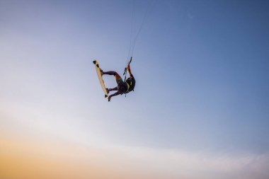 Uçurtma. Bir sörfçü gün batımında güzel bir köprü ve sahil şeridinde sörf yapar ve her türlü gösteriyi sergiler. : Yogyakarta, Endonezya - 26 Ağustos 2023