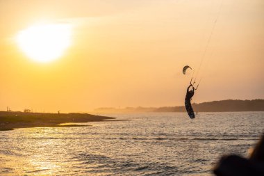 Uçurtma. Bir sörfçü gün batımında güzel bir köprü ve sahil şeridinde sörf yapar ve her türlü gösteriyi sergiler. : Yogyakarta, Endonezya - 26 Ağustos 2023