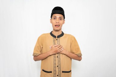 Müslüman kıyafeti giyen Asyalı Müslüman adam ya dua ediyor ya da gönlünü ferahlatıyor. İzole edilmiş beyaz arkaplan.