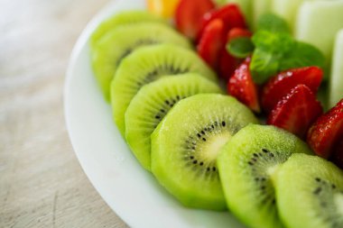 Karpuz, çilek, portakal ve kivi içeren karışık meyve tabağı. Ana odak noktası kivi meyveleri..