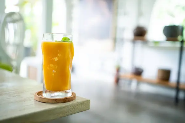 Fresh mango juice on table with luxury home blur background.