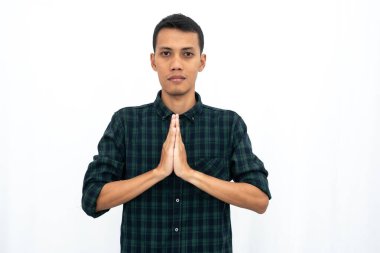 Yeşil kareli bir tişört giyen Asyalı bir adam karşılama olarak poz veriyor. İzole edilmiş beyaz arkaplan.