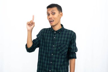 Yeşil kareli bir tişört giyen Asyalı adam reklam için boş bir yeri işaret ediyor. İzole edilmiş beyaz arkaplan.