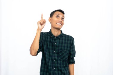 Yeşil kareli bir tişört giyen Asyalı adam reklam için boş bir yeri işaret ediyor. İzole edilmiş beyaz arkaplan.