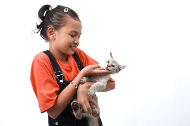 Küçük Asyalı bir kız kedi yavrusunu sevgiyle kucaklıyor. Sevimli. Beyaz arka planda izole edilmiş. Uluslararası kedi günü fotoğraf konsepti.